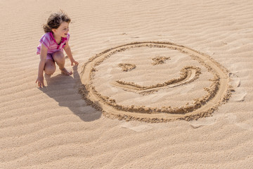 enfant dessinant sur le sable