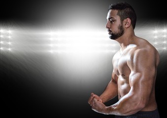 Muscular man posing against black illuminated background