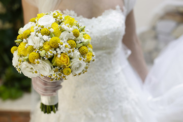 Bellissimo Bouquet da sposa giallo e bianco tenuto in mano con sfondo abito