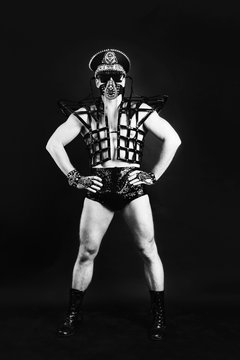 Studio portrait of Dancer Man in black  sexy costume mask and cap with metal elements on black background