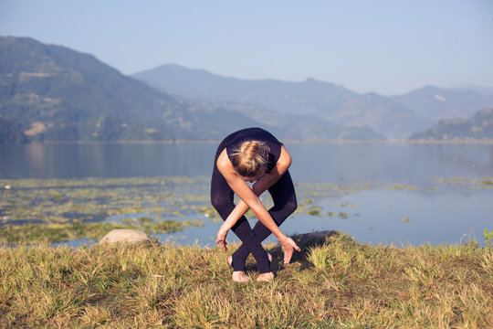 Young woman practicing morning yoga outdoor on mountain lake