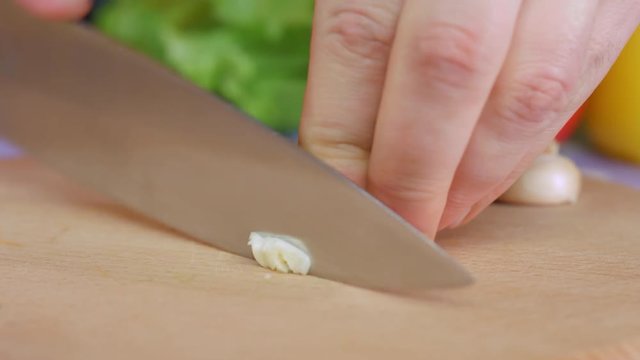 Chopping garlic on wooden board