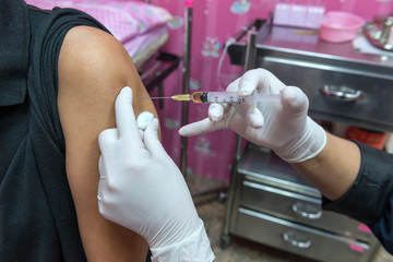 Close-up hands,nurses are vaccinations to patients using the syringe.Doctor vaccinating women in...