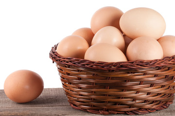 eggs on a wooden table in a wicker basket on a white background