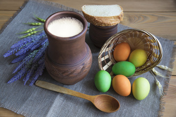 Easter concept. Eggs, a jug of milk mug with a piece of bread and a sprig of lavender.