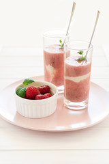 Two glasses with fresh strawberry and banana smoothie decorated mint leaves on white wooden background. Selective focus