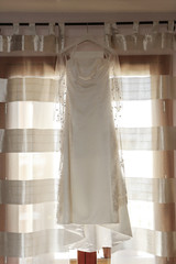 abito da sposa bianco intero appeso sopra una finestra con tenda