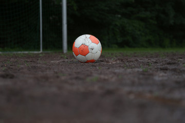 weiss orangefarbener fußball auf matschigen spielfeld