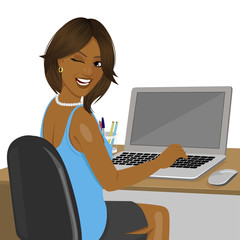 african american woman looking over shoulder sitting in office with laptop winking