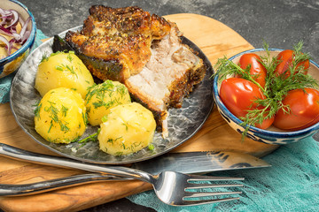 Baked pork with boiled potatoes and marinated mushrooms and tomatoes.