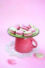 Colored (pink and green) Macarons with Raspberry Cream Filling, on green plate and pink cup, on pink background.