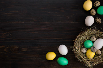 colorful easter eggs in nest on dark vintage wooden background