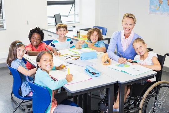 Teacher helping kids with their homework in classroom