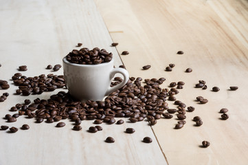 Cup full of coffee beans on wood background