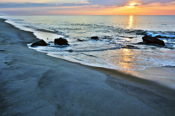 Fototapeta premium Rock Jetty on Beach Beneath A Summer Sunrise