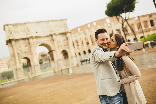 Young couple taking selfie in front of Colosseum in Rome, Italy