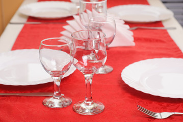Two wine glass on a red tablecloth, decorated table,