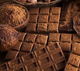 Dark homemade chocolate bars and cocoa pod on wooden