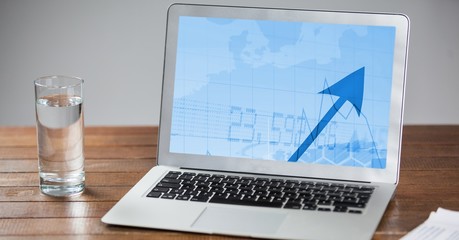 Laptop and glass of water on wooden table 