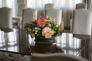 the delicate bouquet of anemones, lilies, lupine, freesia stands on a glass table in the English interior