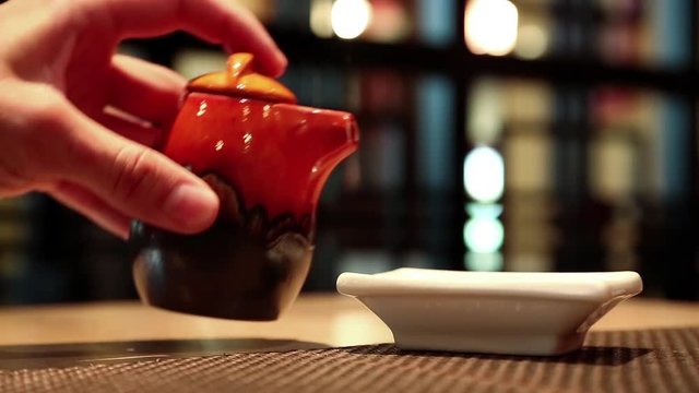 Man in japanese restaurant pours soy sauce. Japanese cuisine