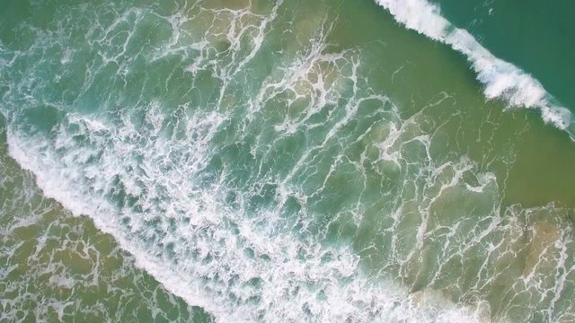 waves of sea run to sandy shore aerial view