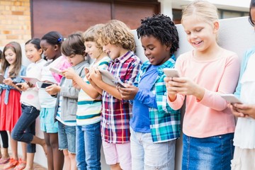Kids using mobile phone and digital tablet on school terrace