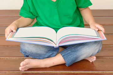 The children are reading a book. She sit on the wooden chair.