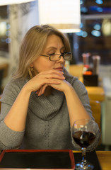 Blonde woman has dinner in japanese restuarant  with sushi and drink red wine