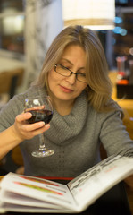 Blonde woman has dinner in japanese restuarant  with sushi and drink red wine