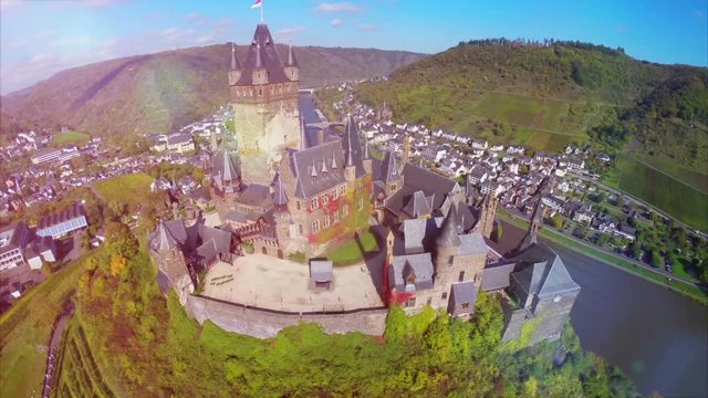 Castle aerial shot, beautiful walls roof tops of medieval fortress on Mosel river in Germany, beauty tourist attraction and family vacation in summer. Ancient castle with vine hills fly over
