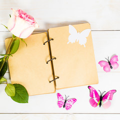 Open vintage notebook or diary with butterfly decoration and rose