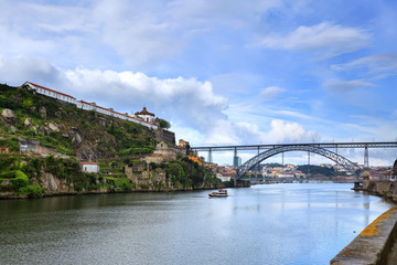 Fototapeta na wymiar Vista panoramica da Ponte Dom Luis na cidade do Porto, com barcos turísticos a passearem no Rio Douro