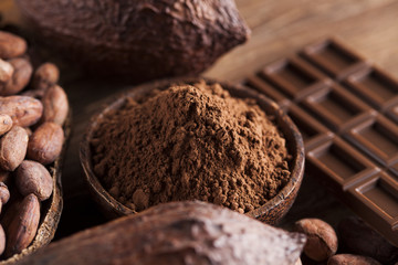 Chocolate bar, candy sweet, cacao beans and powder on wooden background