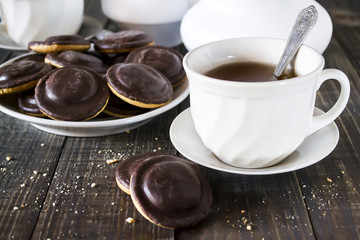 Homemade chocolate chip cookies and hot tea on wooden table.