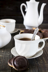 Homemade chocolate chip cookies and hot tea on wooden table.
