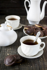 Homemade chocolate chip cookies and hot tea on wooden table.