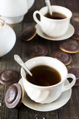 Homemade chocolate chip cookies and hot tea on wooden table.