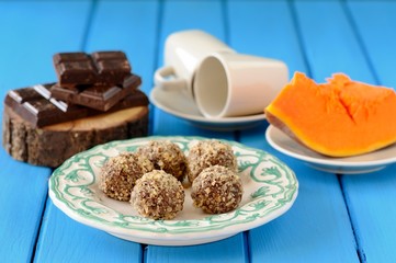 Homemade vegetarian truffles with pumpkin, chocolate and coffee cups on bright blue table