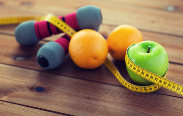 close up of dumbbell, fruits and measuring tape