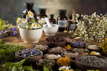 Alternative medicine, dried herbs and mortar on wooden desk background