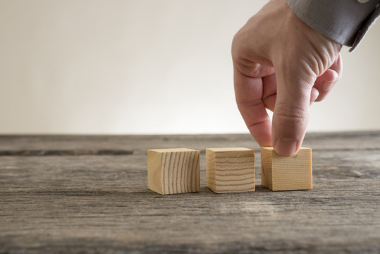 Three wooden empty blocks being placed on a rustic table