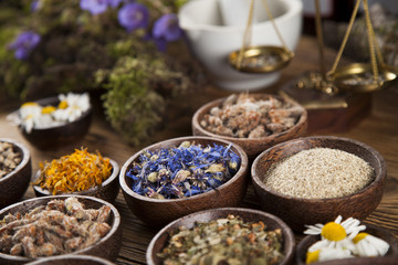 Herbs, berries and flowers with mortar, on wooden table background