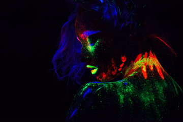 Beautiful extraterrestrial model woman with blue heair and green lips in neon light. It is portrait of beautiful model with fluorescent make-up, Art design of female posing in UV with colorful make up