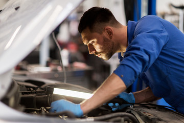 Fototapeta na wymiar mechanic man with lamp repairing car at workshop