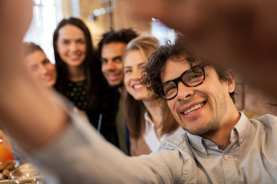 happy man taking selfie with friends at restaurant