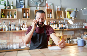 happy man or waiter at bar calling on smartphone