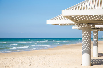 Beach, sea and white sunshades on sunny day. Travel and vacation concept.