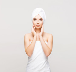 Young, beautiful and natural woman wrapped in towel over grey background.