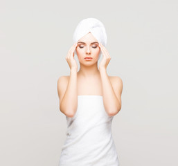Young, beautiful and natural woman wrapped in towel over grey background.